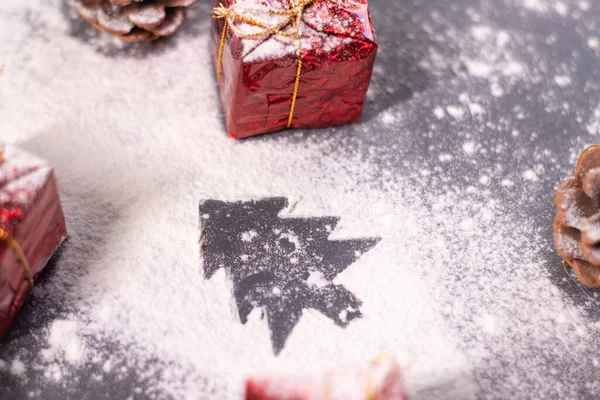 Vánoční ozdoby, dárky a borové šišky ve sněhu a silueta vánočního stromku. Vánoční náladu. Flatly photo — Stock fotografie