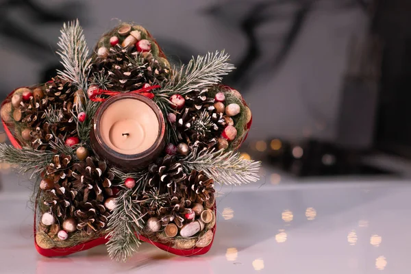 Χριστουγεννιάτικη διακόσμηση σε σχήμα αστεριού από κλαδί δέντρου με παιχνίδια της νέας χρονιάς και ένα κερί σε αυτό — Φωτογραφία Αρχείου