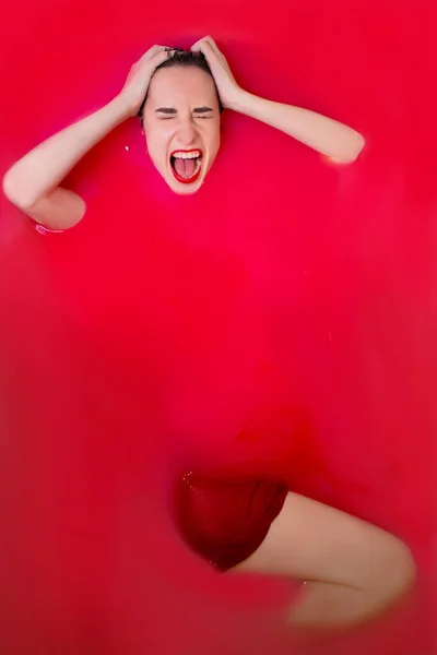 Retrato de una hermosa morena en lencería roja en agua roja. películas de terror. Sesión de fotos en el baño. espacio de copia —  Fotos de Stock