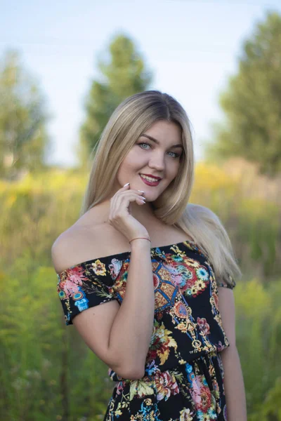 Яркий портрет очаровательной привлекательной блондинки в цветастом платье в поле — стоковое фото