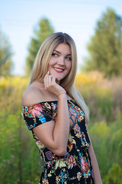 Overlight retrato brillante de una encantadora rubia atractiva en vestido de flores en el campo —  Fotos de Stock