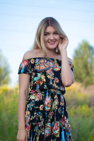 Підсвічування яскравий портрет чарівної привабливої блондинки в квітковому платті в полі — стокове фото