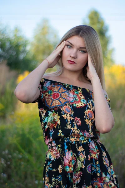 Overlight retrato brillante de una encantadora rubia atractiva en vestido de flores en el campo —  Fotos de Stock