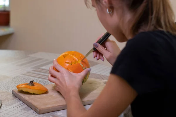Le processus de fabrication d'une citrouille d'Halloween. couper la bouche par une fille brune. thème de l'horreur et Halloween — Photo