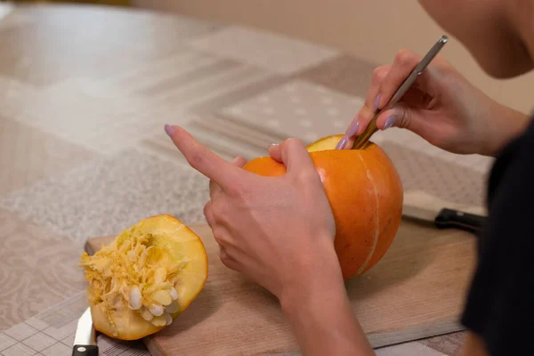 Processen för att göra en Halloween pumpa. Rengöring av frön av en brunett flicka. skräcktema och halloween — Stockfoto