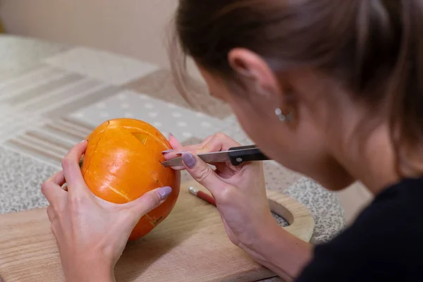 Le processus de fabrication d'une citrouille d'Halloween. couper la bouche par une fille brune. thème de l'horreur et Halloween — Photo