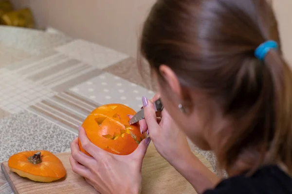 Le processus de fabrication d'une citrouille d'Halloween. couper la bouche par une fille brune. thème de l'horreur et Halloween — Photo