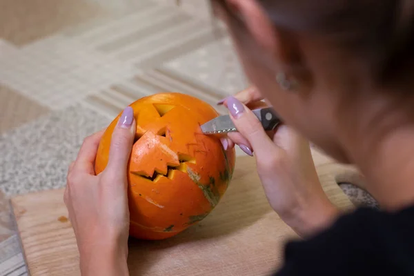 El proceso de hacer una calabaza de Halloween. cortando la boca por chica morena. tema de terror y Halloween —  Fotos de Stock