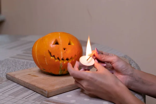 Der Prozess der Herstellung eines Halloween-Kürbisses. Zünden Sie ein Streichholz und eine Kerze an. Horror-Thema und Halloween — Stockfoto