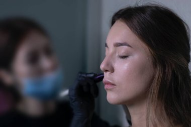 Tıbbi maske ve siyah eldiven ustası güzel esmerlere makyaj yapma süreci. güzellik ve kozmetik konsept