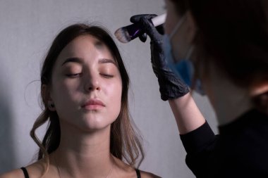 Tıbbi maske ve siyah eldiven ustası güzel esmerlere makyaj yapma süreci. güzellik ve kozmetik konsept