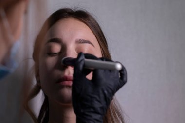 Tıbbi maske ve siyah eldiven ustası güzel esmerlere makyaj yapma süreci. güzellik ve kozmetik konsept