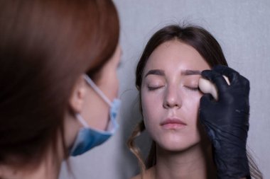 Tıbbi maske ve siyah eldiven ustası güzel esmerlere makyaj yapma süreci. güzellik ve kozmetik konsept