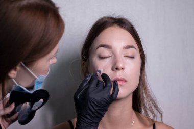 Tıbbi maske ve siyah eldiven ustası güzel esmerlere makyaj yapma süreci. güzellik ve kozmetik konsept