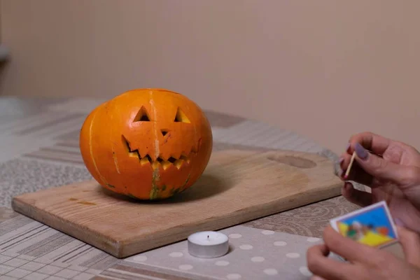 El proceso de hacer una calabaza de Halloween. enciende una cerilla y una vela. tema de terror y Halloween —  Fotos de Stock