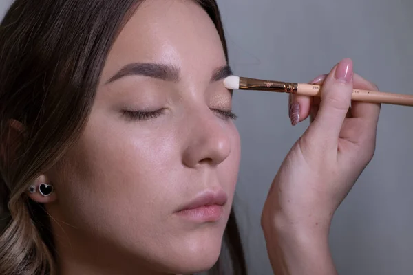 The process of applying makeup to a beautiful brunette. beauty, modeling and cosmetics concept — Stock Photo, Image