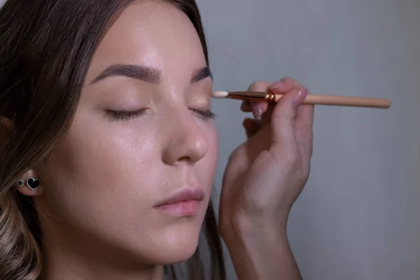Het proces van het aanbrengen van make-up op een mooie brunette. schoonheid, modellering en cosmetica concept — Stockfoto