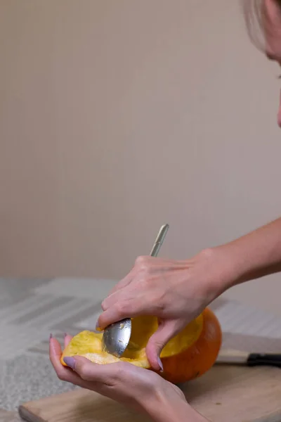 Le processus de fabrication d'une citrouille d'Halloween. nettoyage des graines par une fille brune. thème de l'horreur et Halloween — Photo