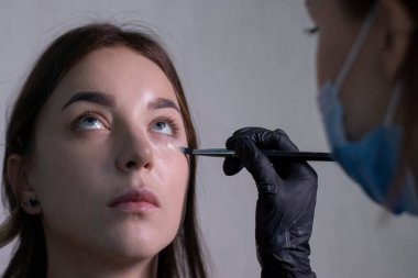 Tıbbi maske ve siyah eldiven ustası güzel esmerlere makyaj yapma süreci. güzellik ve kozmetik konsept