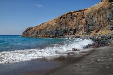 Atlantik Okyanusu dalgaları tarafından yıkanmış siyah volkanik kum ile ünlü Madeira Adası plaj. Arka plan, renkli kaya oluşumu. Kopya alanı ile tebrik kartı. Popüler turizm.