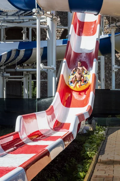 Father and son on steep red and white waterslide — Stock Photo, Image