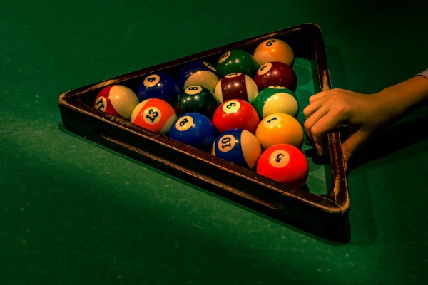 Segurando triângulo de madeira com bolas na mesa verde — Fotografia de Stock
