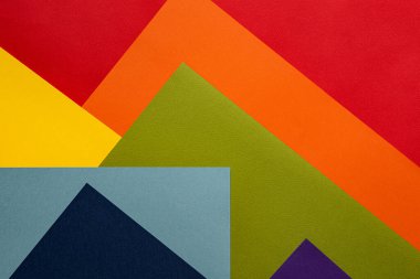 Gökkuşağı renklerinde geometrik desenli renkli ve kağıt ve karton desenli renkli bir arkaplan. Doğrudan görünümün üzerinde.