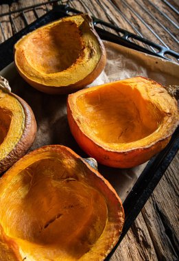 Ev yapımı portakal kabakları fırın tepsisinde, fırın tepsisinde ve doğal desenli ahşap masada. Kırsal tarzda. Dikey oryantasyon. Seçici odaklanma. Yüksek açı. Doğal ışık.