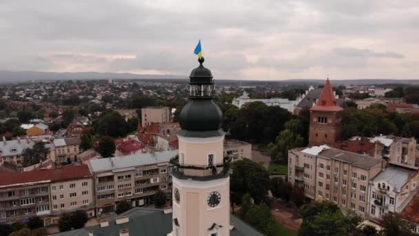 Башня мэрии города Дрогобыча с флагом Украины. Полет вокруг башни с пейзажем на город, пасмурный, осень — стоковое видео