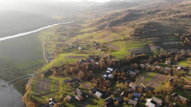 Vista aérea da antiga aldeia em Cárpatos com arquitetura tradicional, campos, estradas e rio. Tempo de outono, viajar para o oeste da Ucrânia. Voar para a frente — Vídeo de Stock