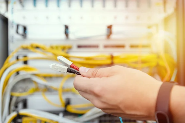 IT specialist connects fiber optic cables to the network equipment. IT infrastructure and data line