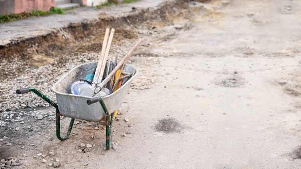 Wheelbarrow with working tool in the middle of road, road repair work