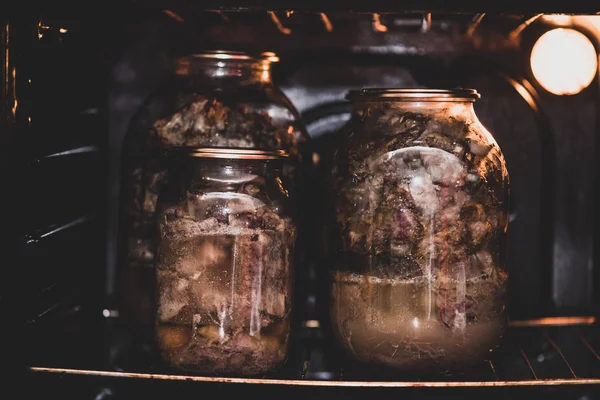 Frascos de vidrio con un cerdo estofado en horno caliente. Cocina casera con una receta tradicional. Técnica de tonificación mate — Foto de Stock