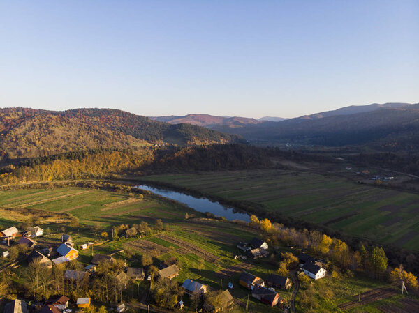 Aerial Drone View of autumn mountains with forests and river, meadows and hills in sunset soft light. Carpathian Mountains, Ukraine