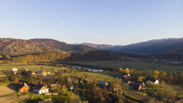 Karpat Dağları, Ukrayna. Gün batımında ormanlar ve nehir, çayırlar ve tepeler ile sonbahar dağlarının Havadan Drone Görünümü yumuşak ışık