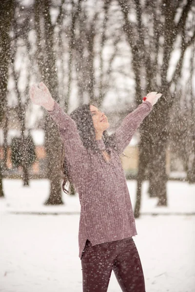 Mooie jongedame is genieten van de sneeuw het verstrooiing in de lucht, positieve emoties, vreugde en geluk. Winterpret buitenshuis — Stockfoto