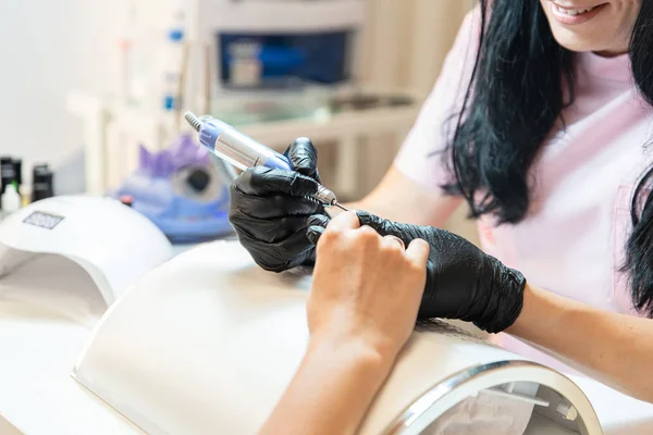Profesjonalny kosmetyczka sprawia, że manicure dla kobiety za pomocą elektrycznego pliku paznokci. Zamknij proces. Kobieta w salonie piękności. Uroda i samoopieka — Zdjęcie stockowe