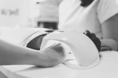 Güzellik salonundaki kadın. Uv Led tırnak lambası taze manikür ile el. Tırnaklarda jel kurutma, süreci closeup. Güzellik ve öz bakım. Tek renkli tonlama