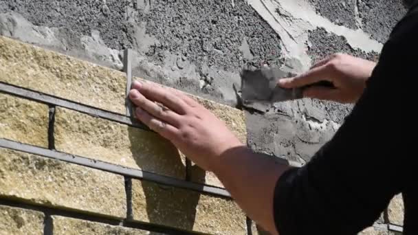 男は装飾的なレンガで壁のファサードを飾る ビューを閉じます 建築物の壁を被覆するプロセス — ストック動画