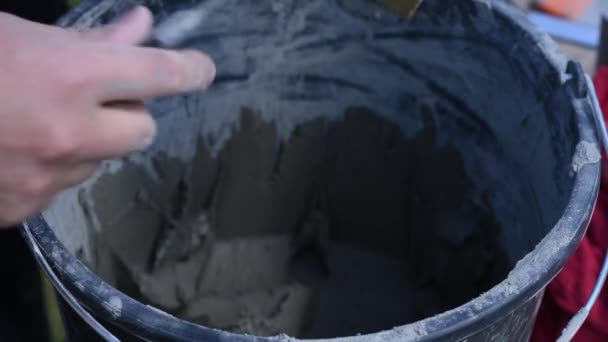 Hombre Toma Cola Del Cubo Pone Con Espátula Sobre Ladrillo — Vídeos de Stock