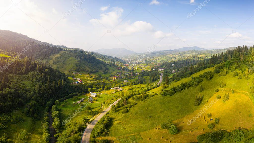 Scenic panoramic landscape. Aerial drone view of picturesque urban-type settlement in valley among green nature, coniferous forests, and Carpathians mountains. Popular tourists place.