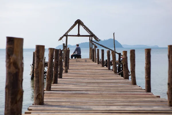 Старий сидить на пірсі і дивиться на море Ліцензійні Стокові Фото