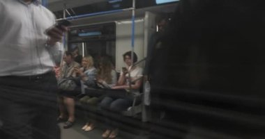 Moskova, Rusya - Temmuz 2019: Metro vagonunda seyahat eden yolcular, kapıdaki camın yansımasından ateş ediyor