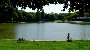 Moskova, Rusya - Ağustos 2019: Gölet üzerinde yaz şehir Park bir olta ile Balıkçı