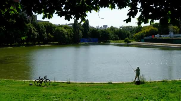 Moskau, russland - august 2019: fischer mit angelrute im sommerlichen stadtpark am teich — Stockvideo