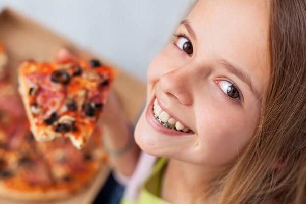 Closeup portrait of a happy young teenager about to eat a slice of pizza - smiling with anticipation, top view