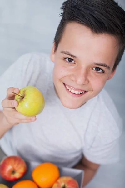 Menino adolescente saudável feliz com um prato de frutas - segurando um — Fotografia de Stock