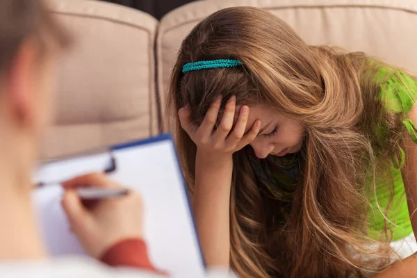 Counseling and support professional taking notes about a sad tee — Stock Photo, Image