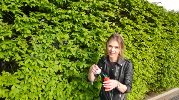 Усміхнена красива дівчина дме мильні бульбашки в літньому парку — стокове відео