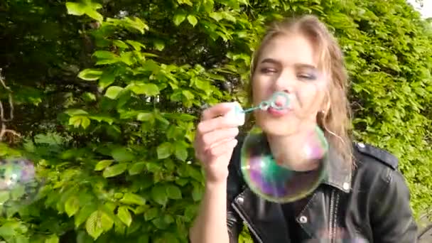 Happy smiling woman blowing bubbles in the park — Stock Video